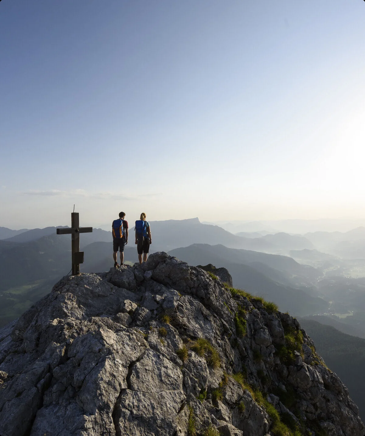 Zwei Wanderer auf einem Berggipfel mit Gipfelkreuz - aus der Ferne fotografiert | © DAV/Wolfgang Ehn